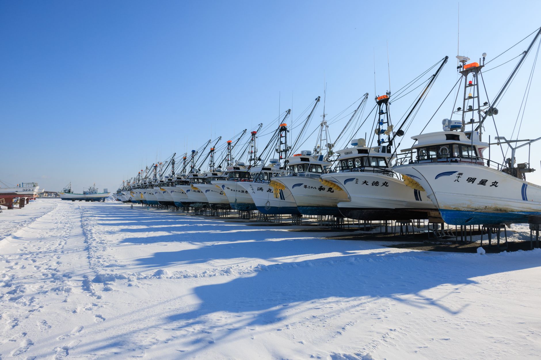 雪の上に陸揚げされた漁船が並ぶ北海道の漁港