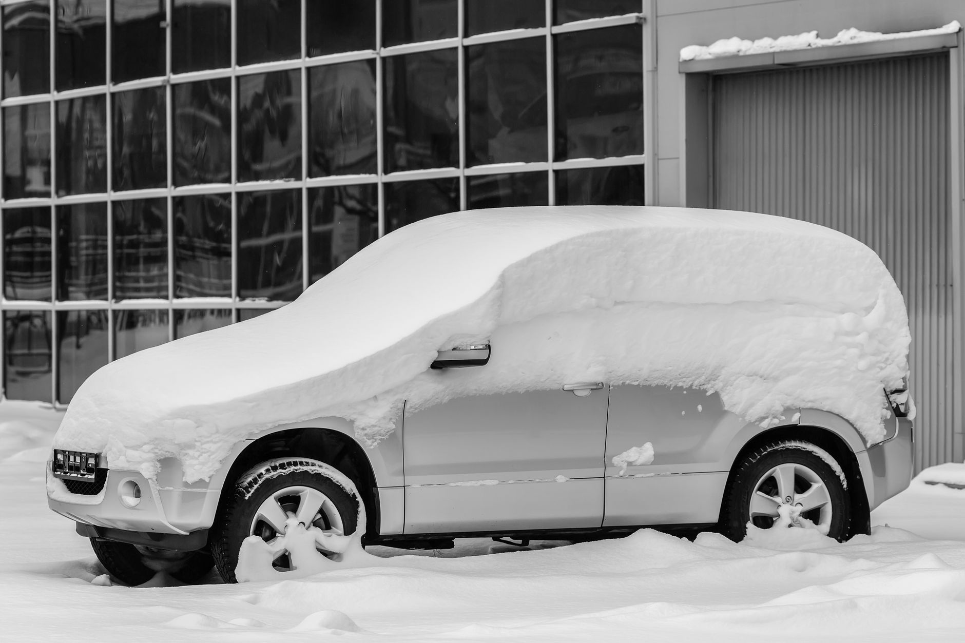 厚い雪にすっぽり覆われた駐車中の車(イメージ)
