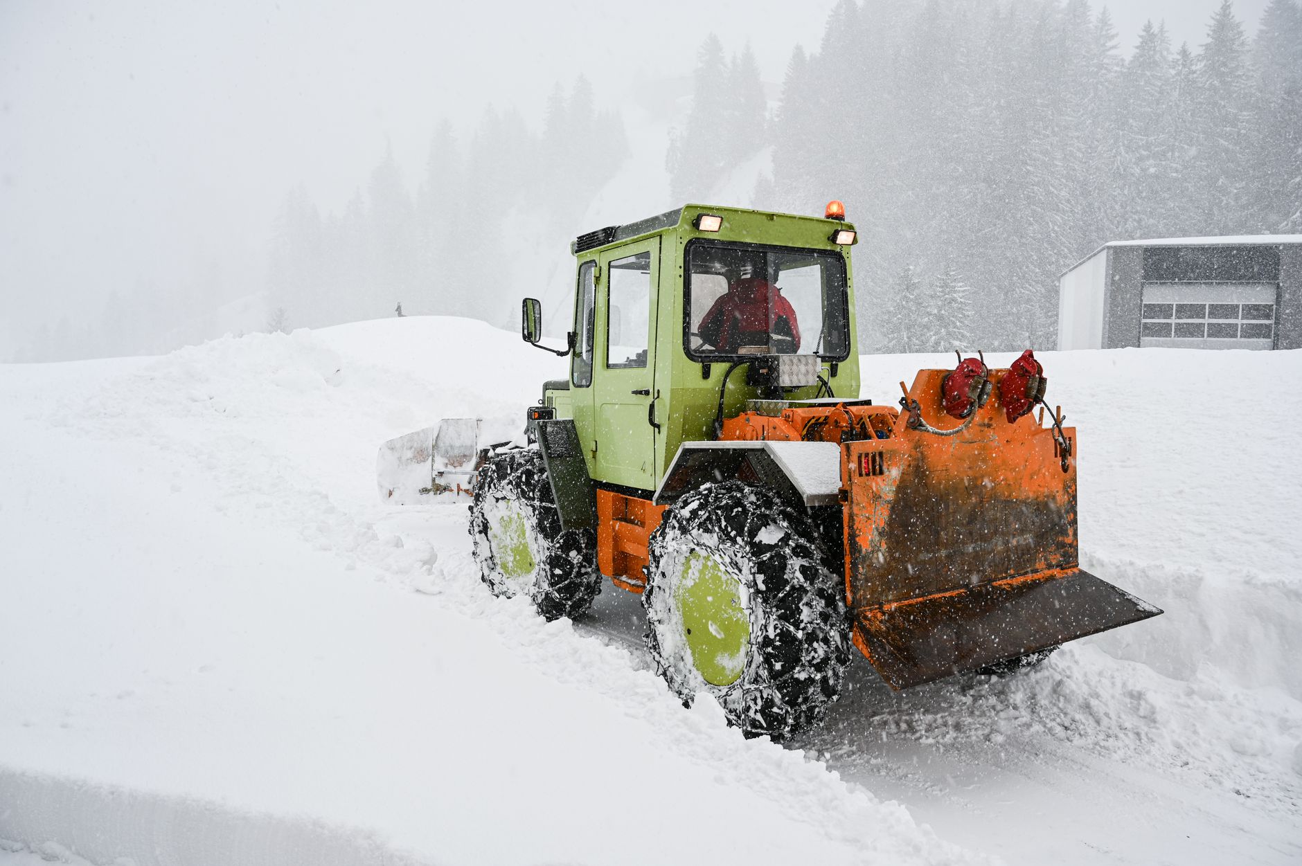 吹雪のなかで除雪作業をする除雪車(イメージ)