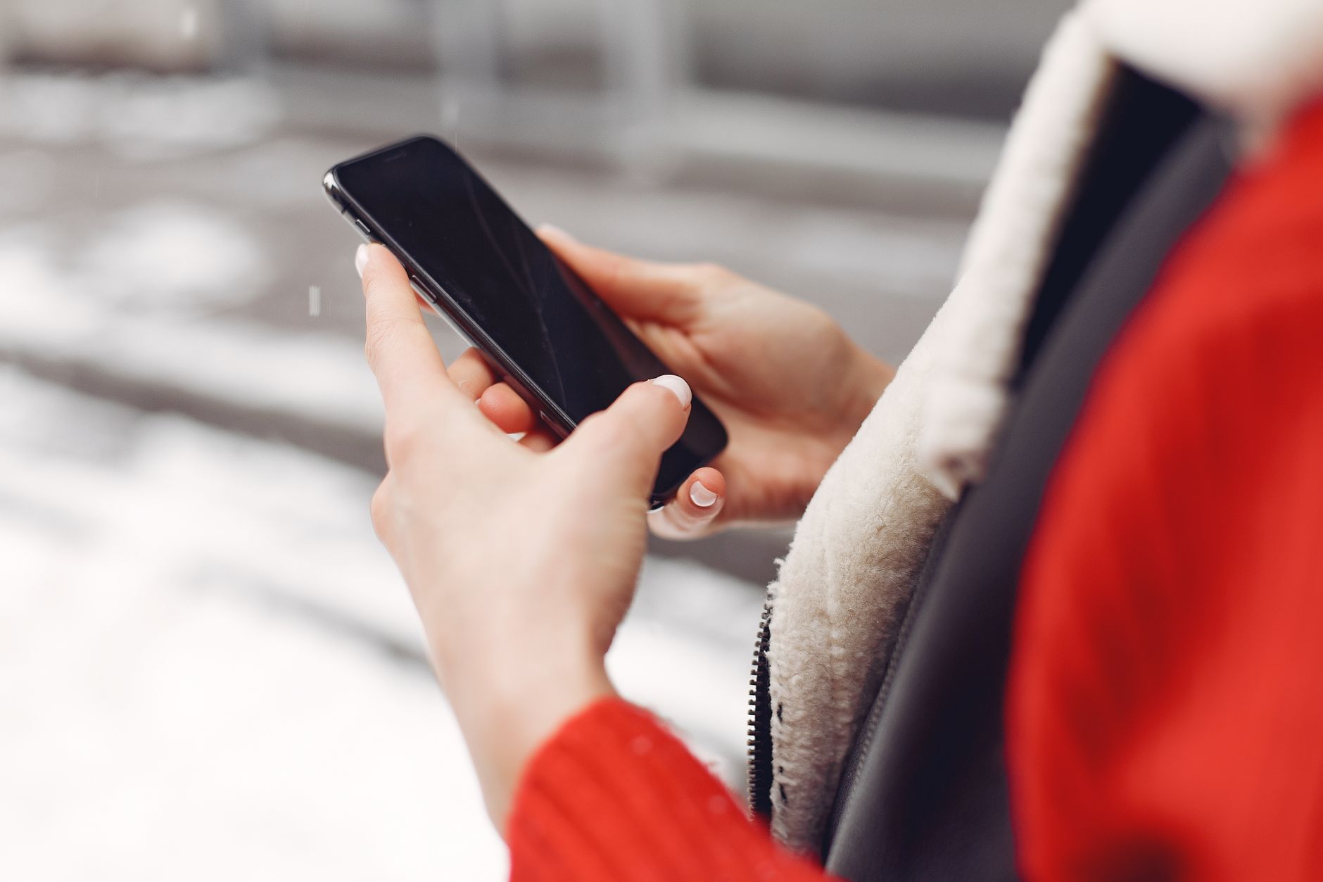 雪の屋外でスマートフォンを操作する旅行者の手元(イメージ)