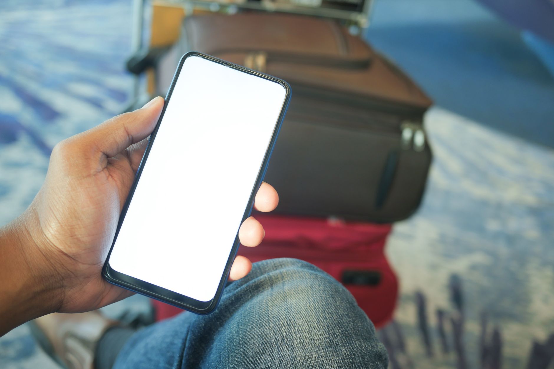 空港でスマートフォンを手に予約状況を確認する人(イメージ)