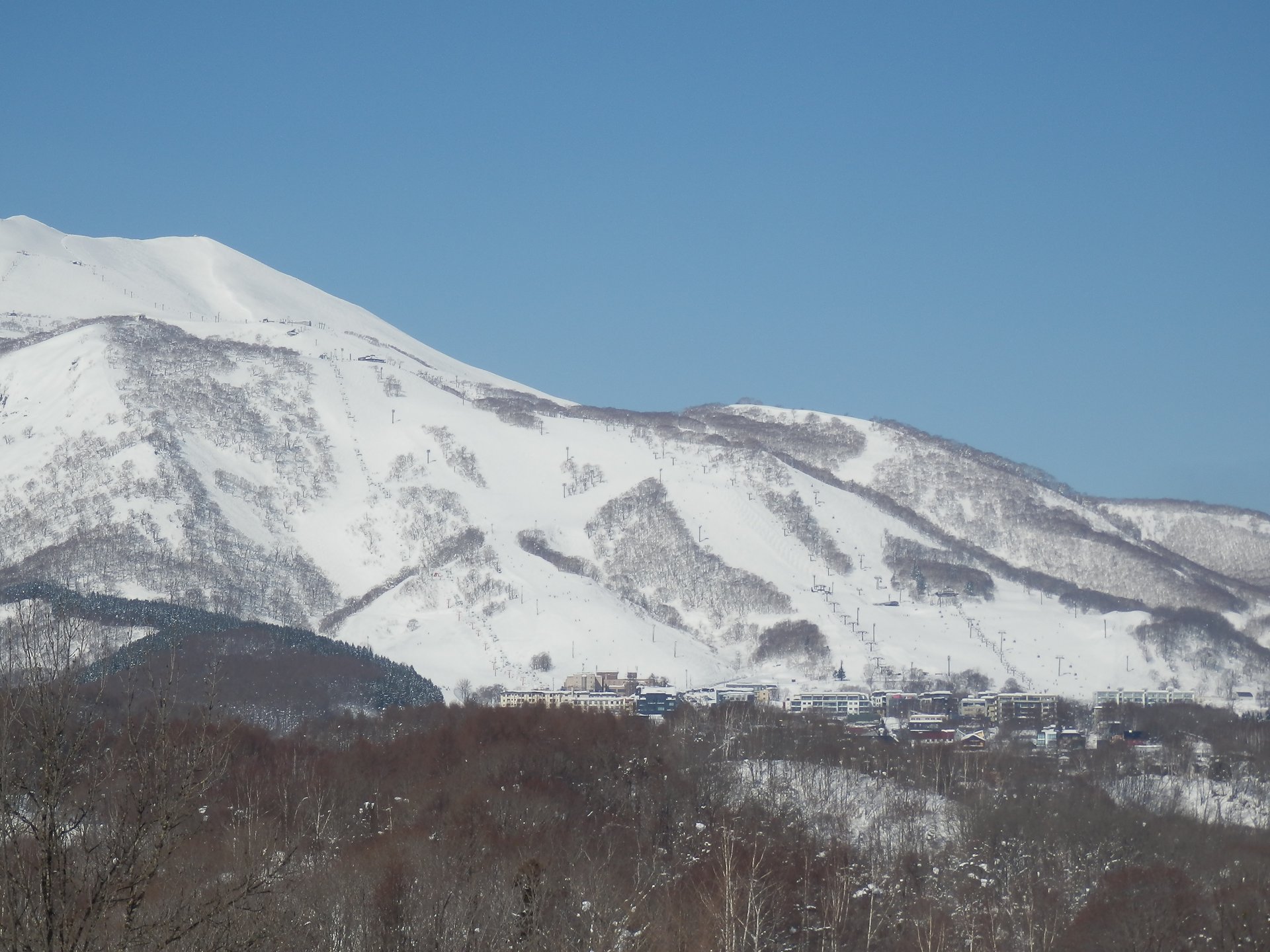 JR比羅夫駅付近から見た、雪に覆われた山とグラン・ヒラフのゲレンデ
