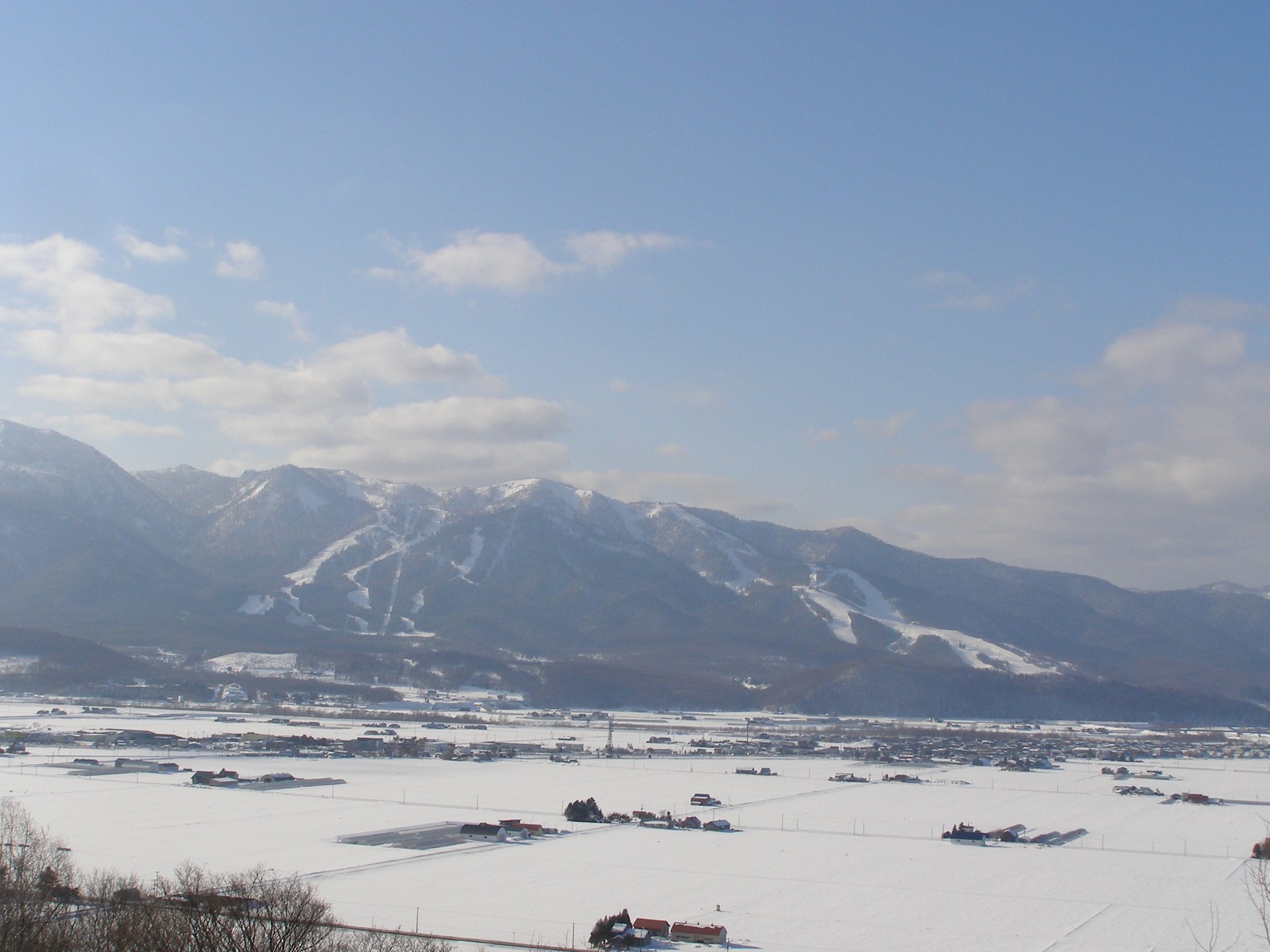 雪原の向こうに見える富良野スキー場のゲレンデと山並みの遠景