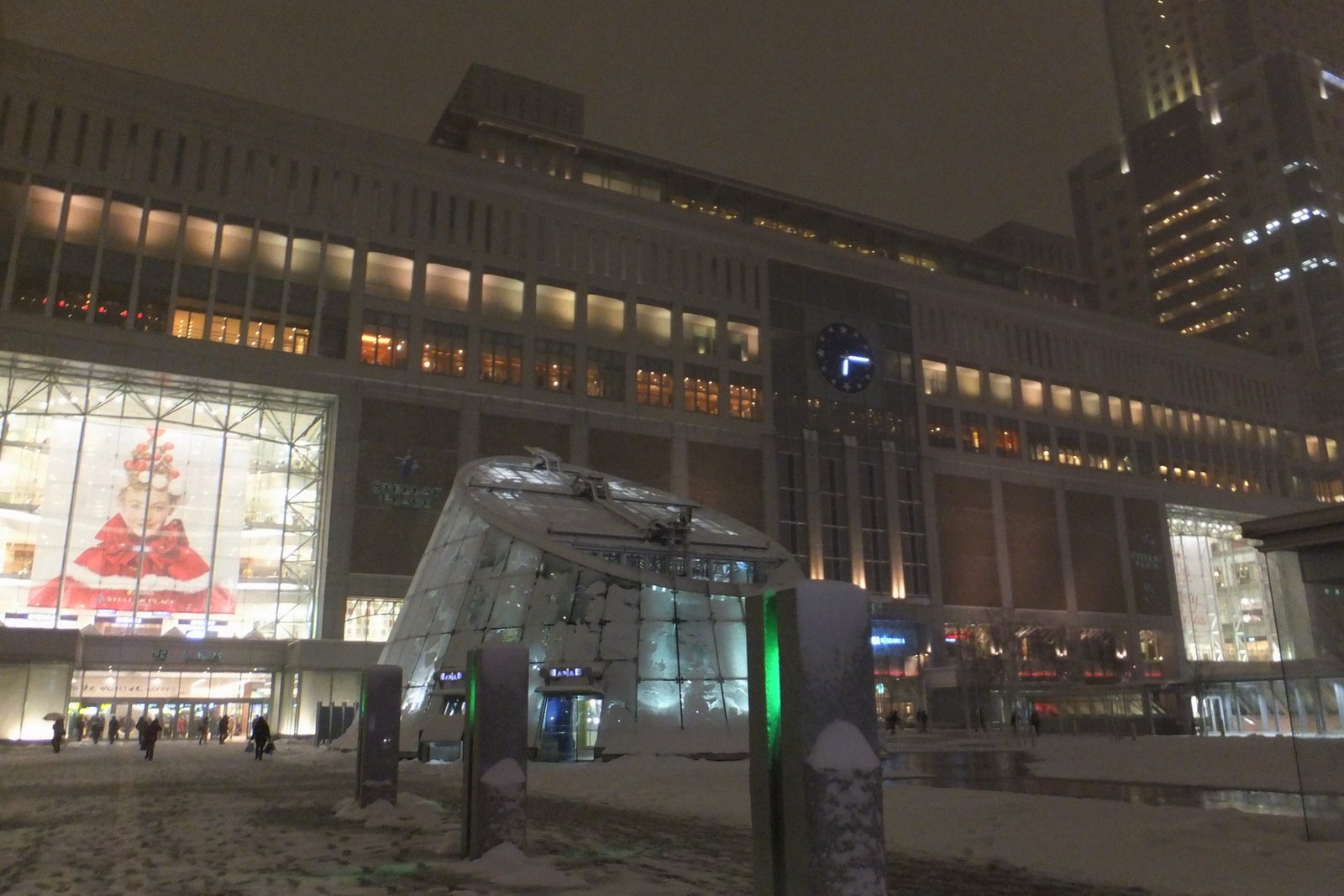 雪が降る夜のJR札幌駅南口。駅ビルの明かりと雪の積もった広場