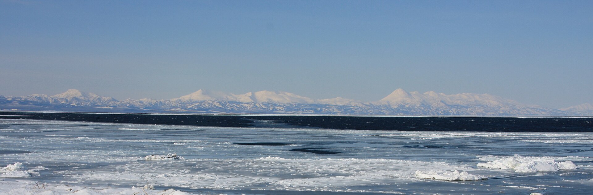 流氷が浮かぶ根室海峡の向こうに、雪をかぶった知床連山が横一列に連なる