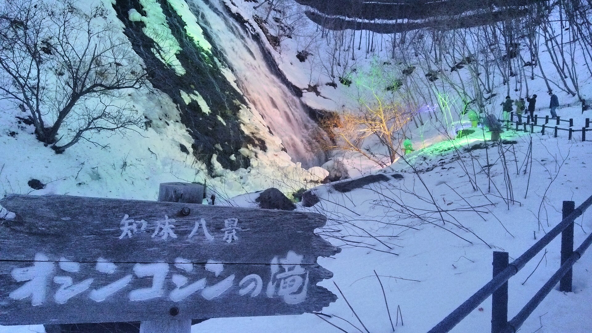 雪に囲まれたオシンコシンの滝。手前に「知床八景 オシンコシンの滝」と書かれた木の看板がある