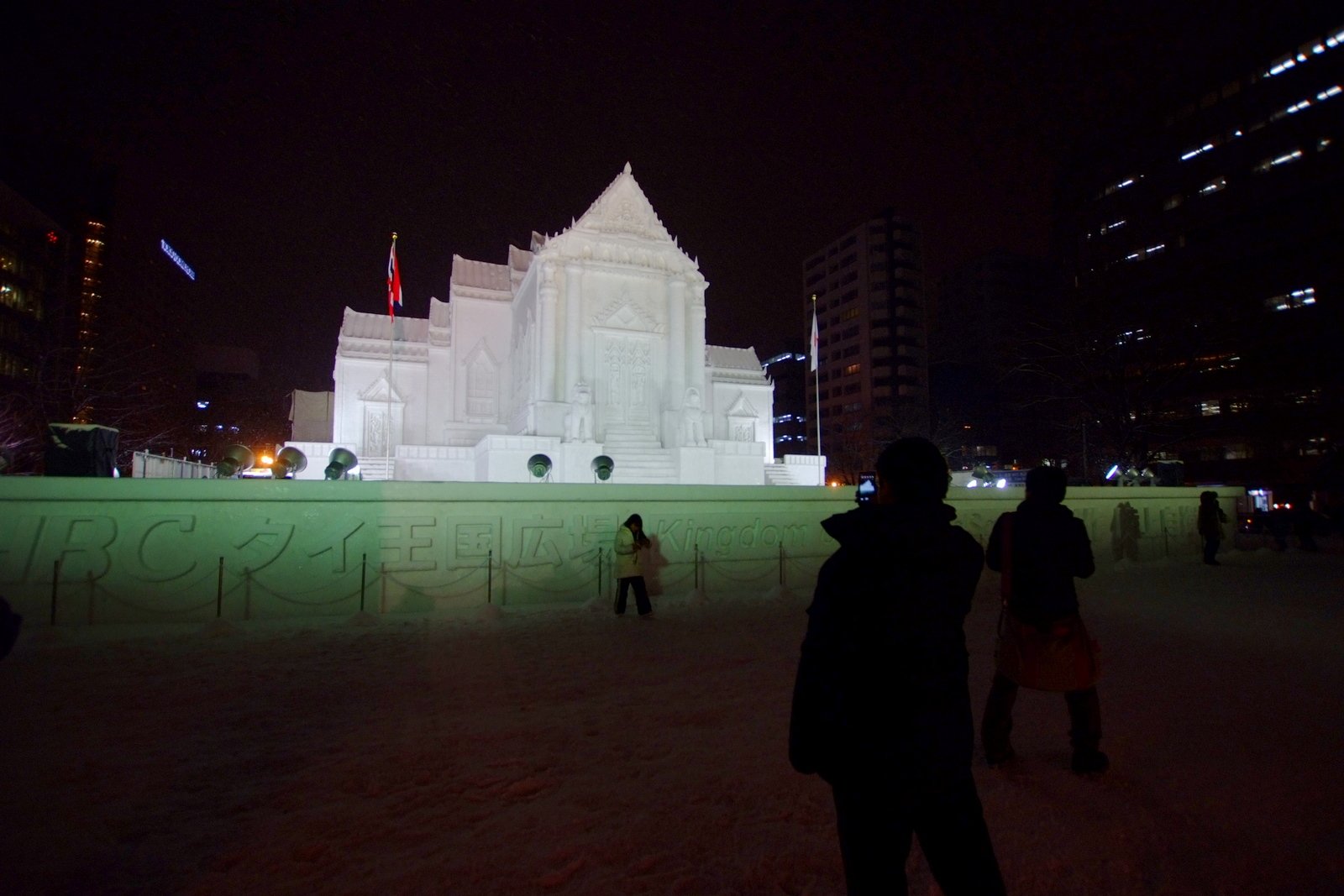 夜のさっぽろ雪まつり大通会場。ライトアップされた寺院をかたどった大雪像と見物客のシルエット(第64回)