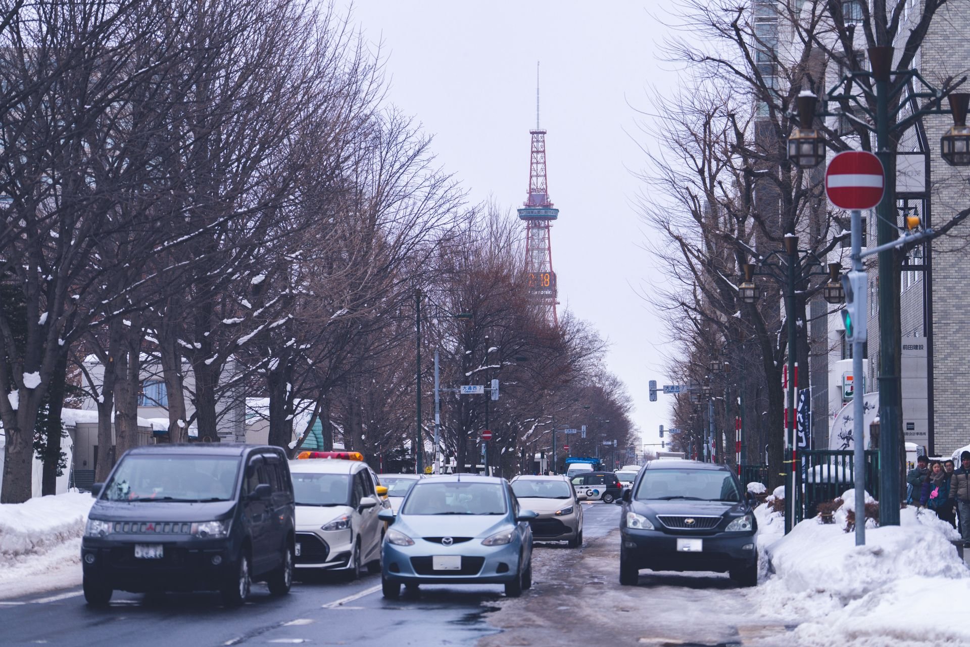 雪の残る冬の札幌の並木道。並木の先にさっぽろテレビ塔が見える
