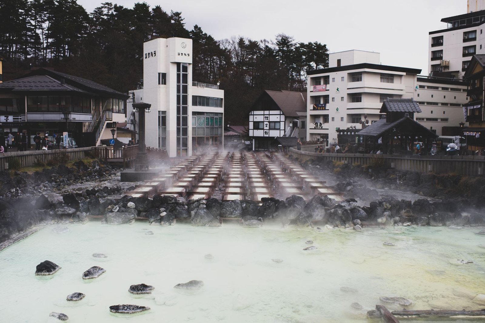 源泉から白い湯気が立ちのぼる温泉街の風景（イメージ）