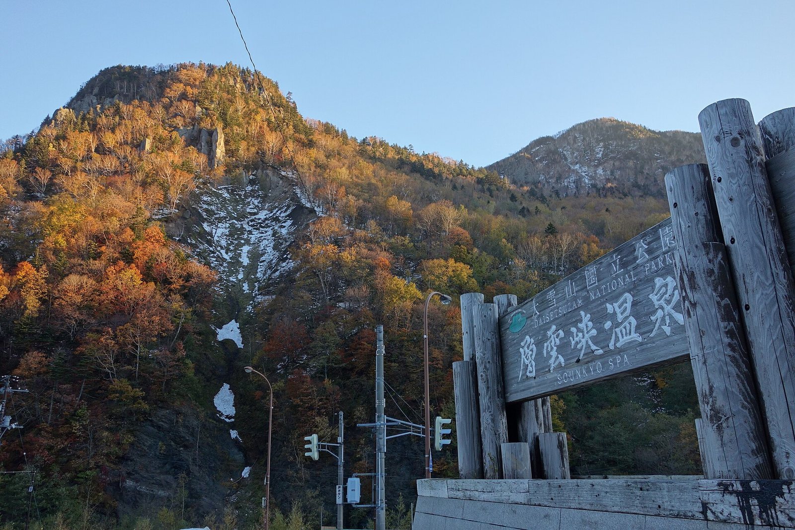 大雪山国立公園・層雲峡温泉と記された木造の看板と、背後にそびえる断崖