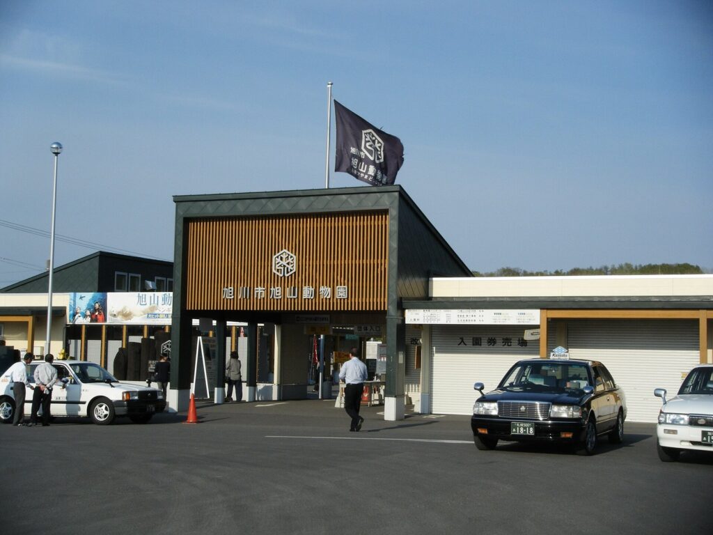 「旭川市旭山動物園」の看板を掲げた正門と、門前に停まるタクシー