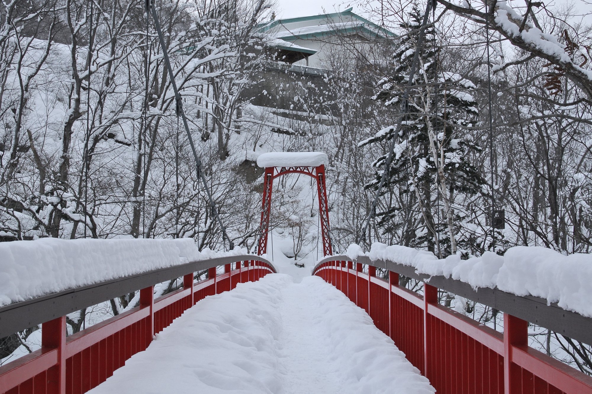 雪に覆われた冬の定山渓温泉(札幌市南区)の赤い欄干の橋
