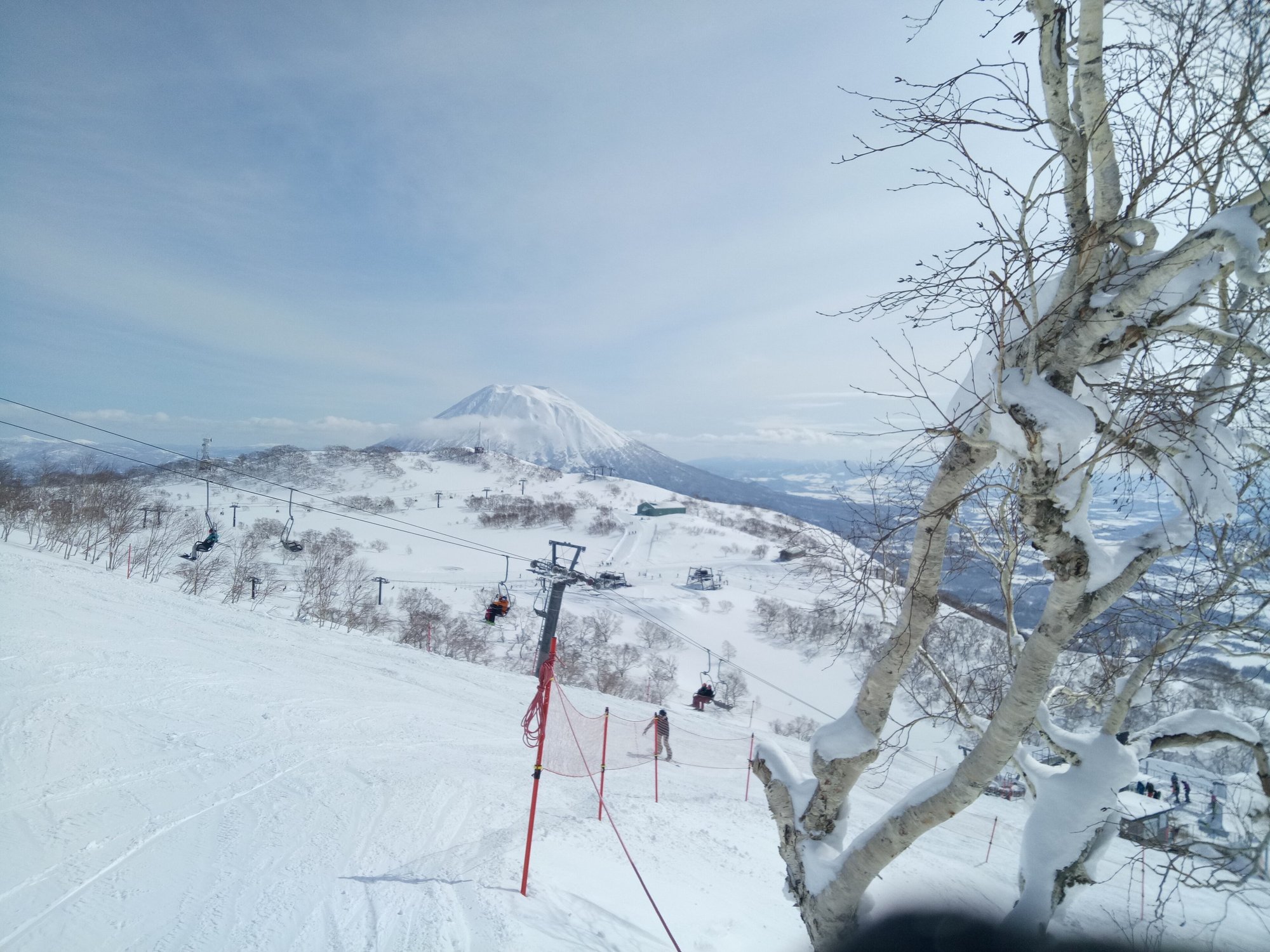 ニセコのスキー場のゲレンデとリフト、遠くにそびえる雪化粧の羊蹄山