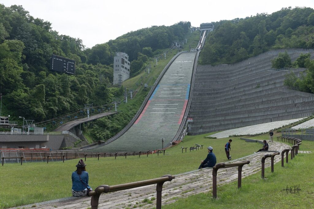 夏の大倉山ジャンプ競技場。ジャンプ台を見上げる芝生に見学者がいる