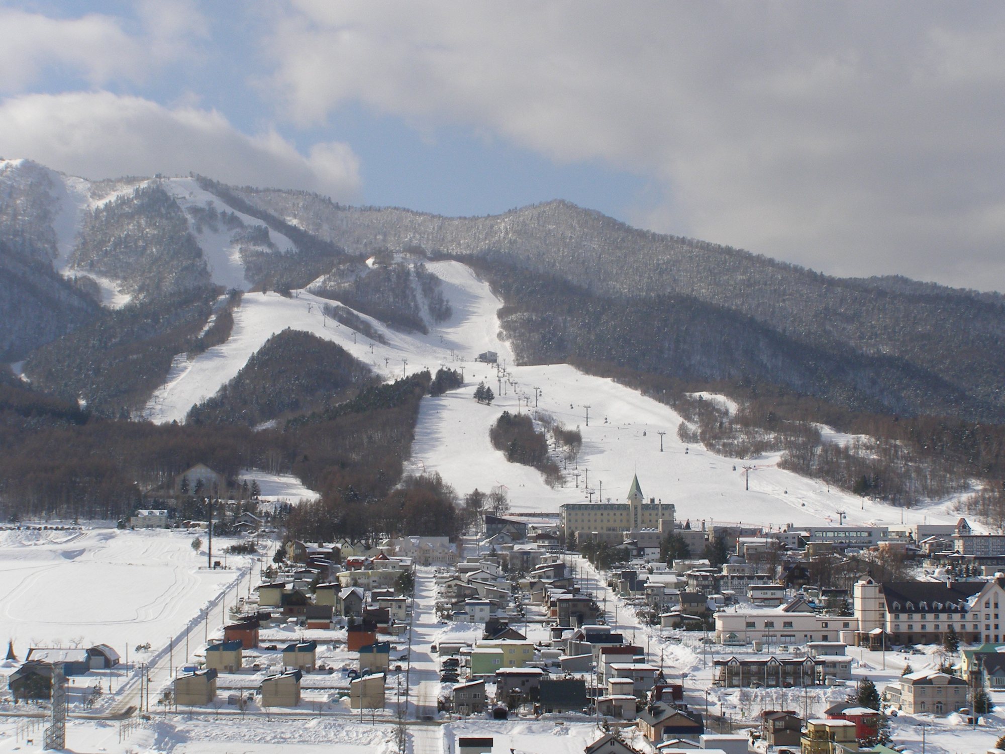 富良野の街並みの奥に広がる富良野スキー場北の峰ゲレンデの雪の斜面