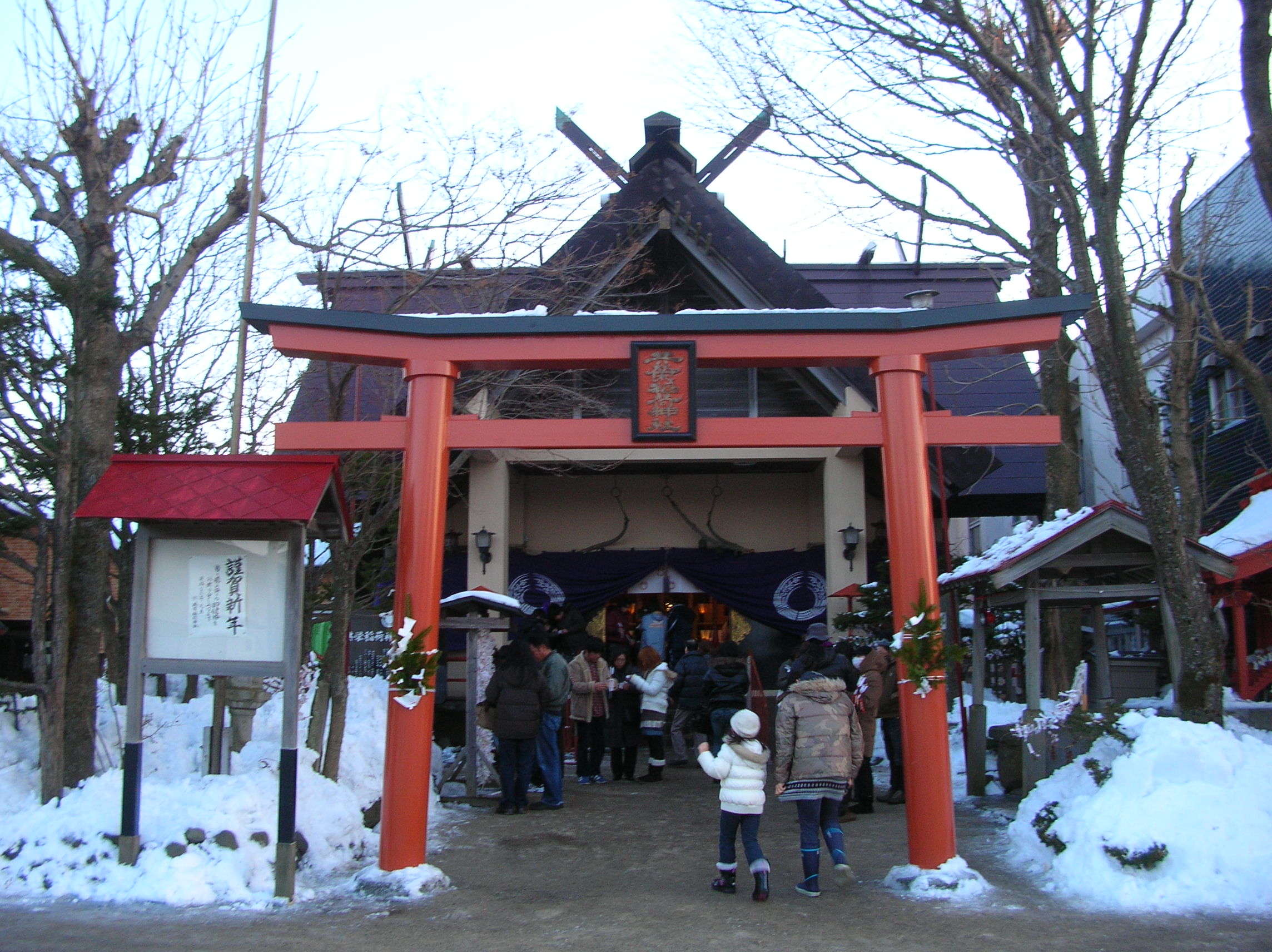 境内の脇に雪が残る元日の釧路・共栄稲荷神社と参拝客