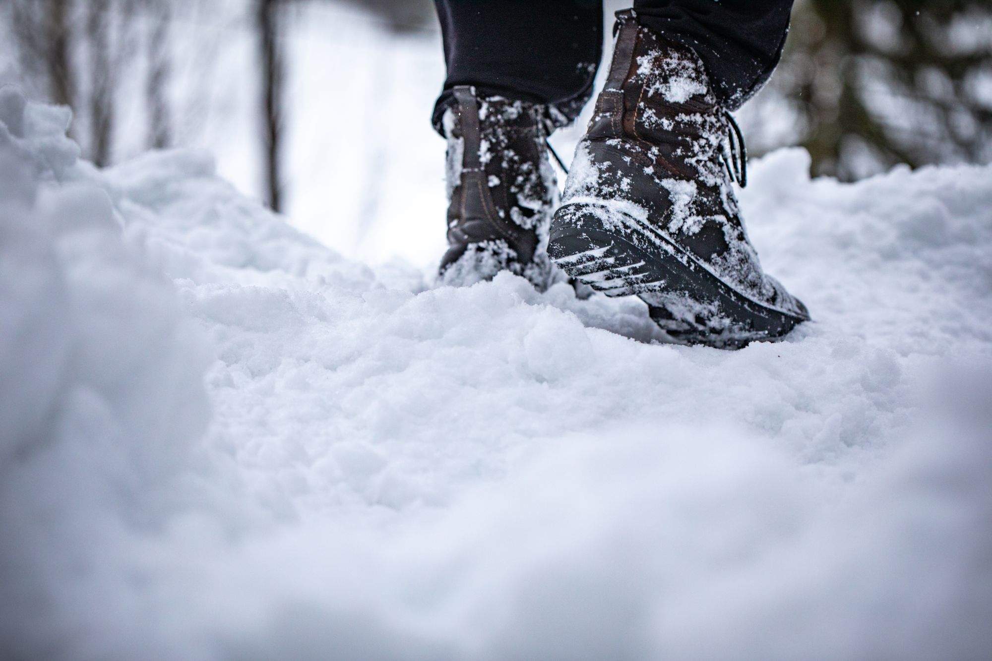 深い雪の中を歩く、雪にまみれた冬用ブーツの足元