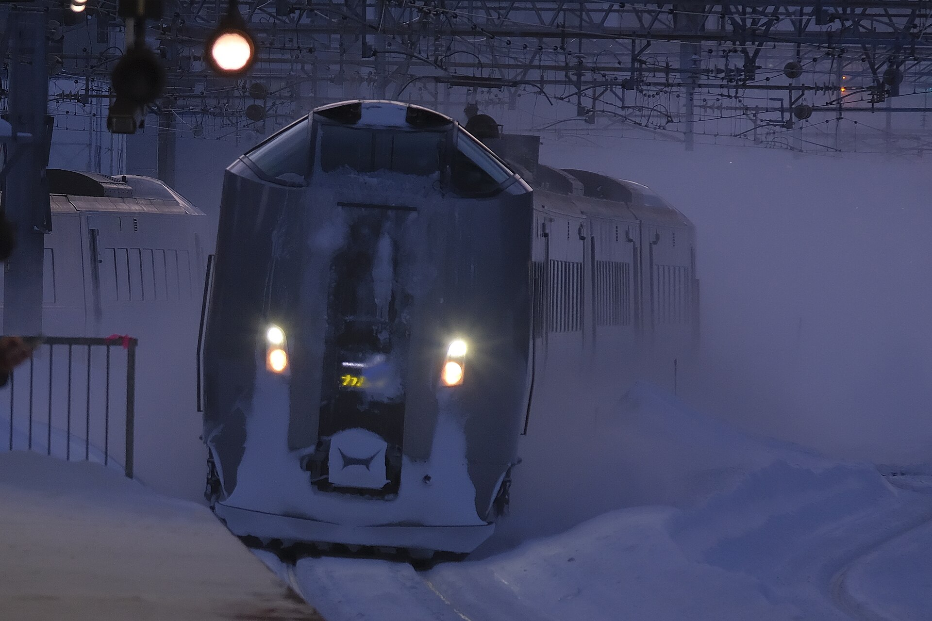 雪煙を上げながら冬の苗穂駅を通過する特急カムイの789系1000番台