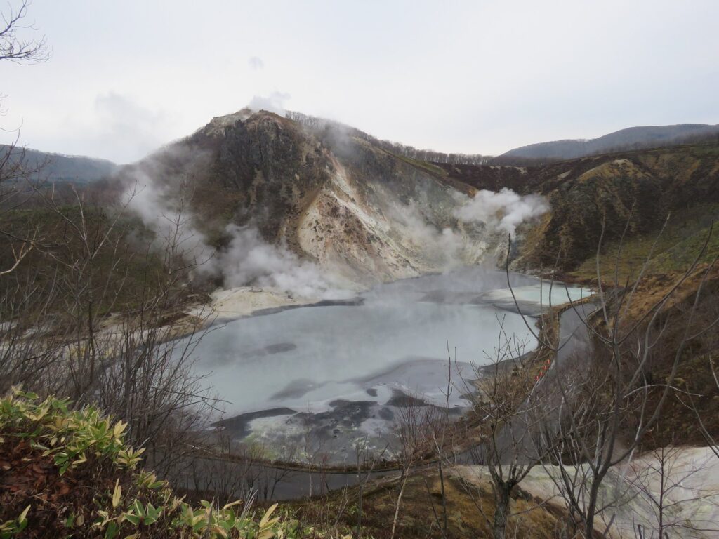 湯気が立ち上る大湯沼と背後にそびえる日和山