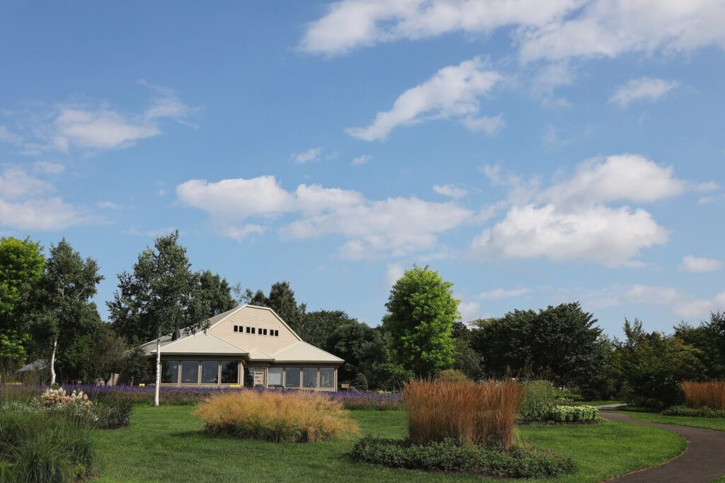青空の下、花壇と芝生の奥に建物が見える十勝ヒルズの庭園