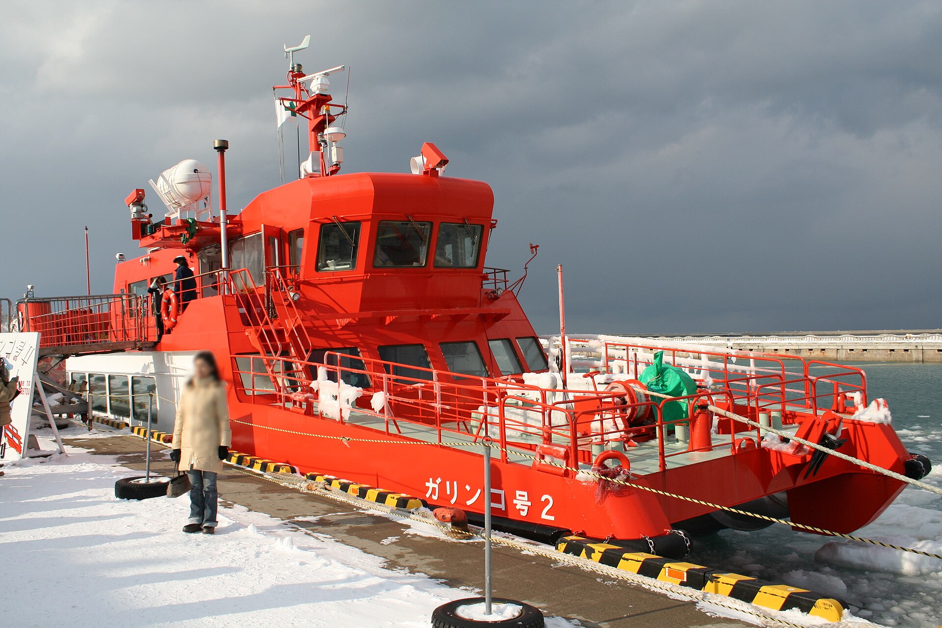 雪の積もった岸壁に接岸している赤い船体の砕氷観光船。船体に「ガリンコ号2」の文字がある