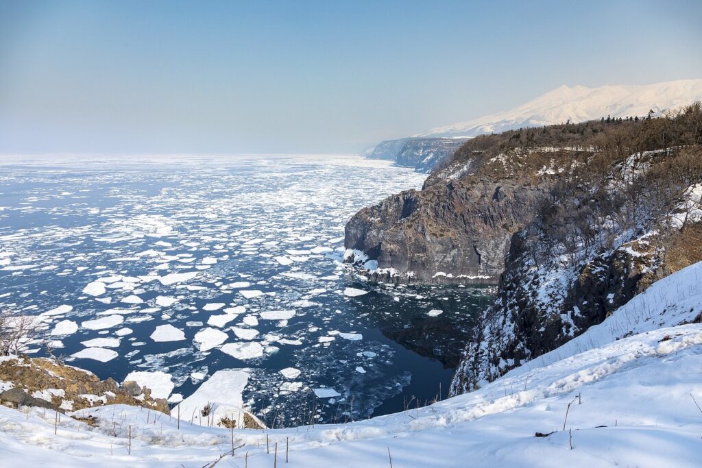 雪の積もった知床半島の断崖とオホーツク海を埋める流氷