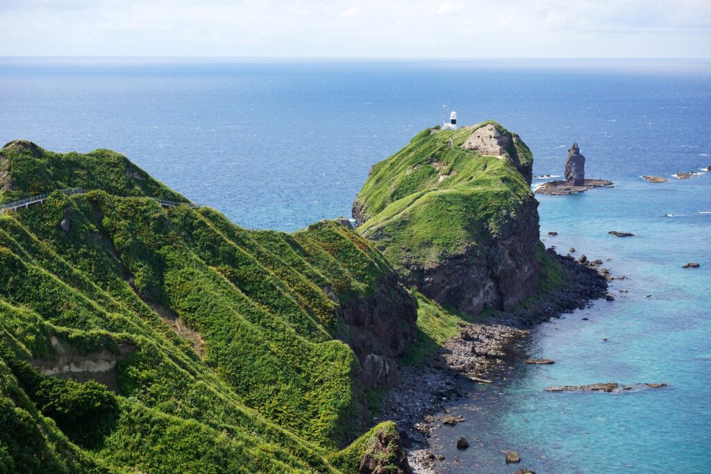 灯台が立つ神威岬の先端と、沖に立つ神威岩