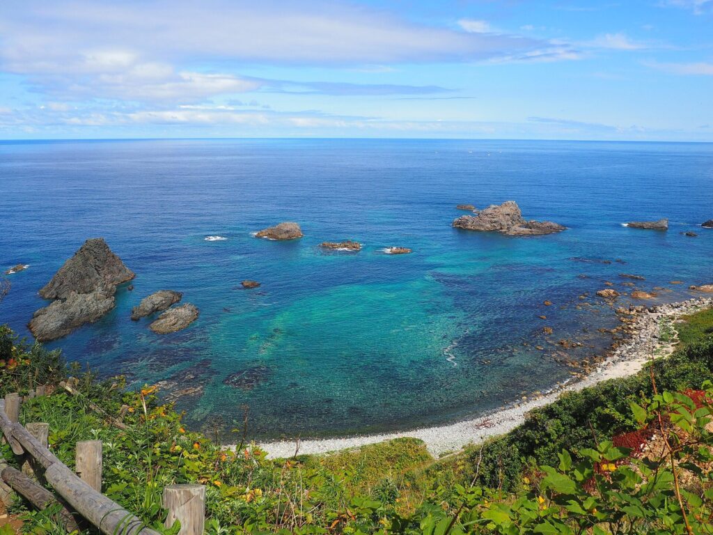 高台から見下ろす島武意海岸の青い入り江と岩礁