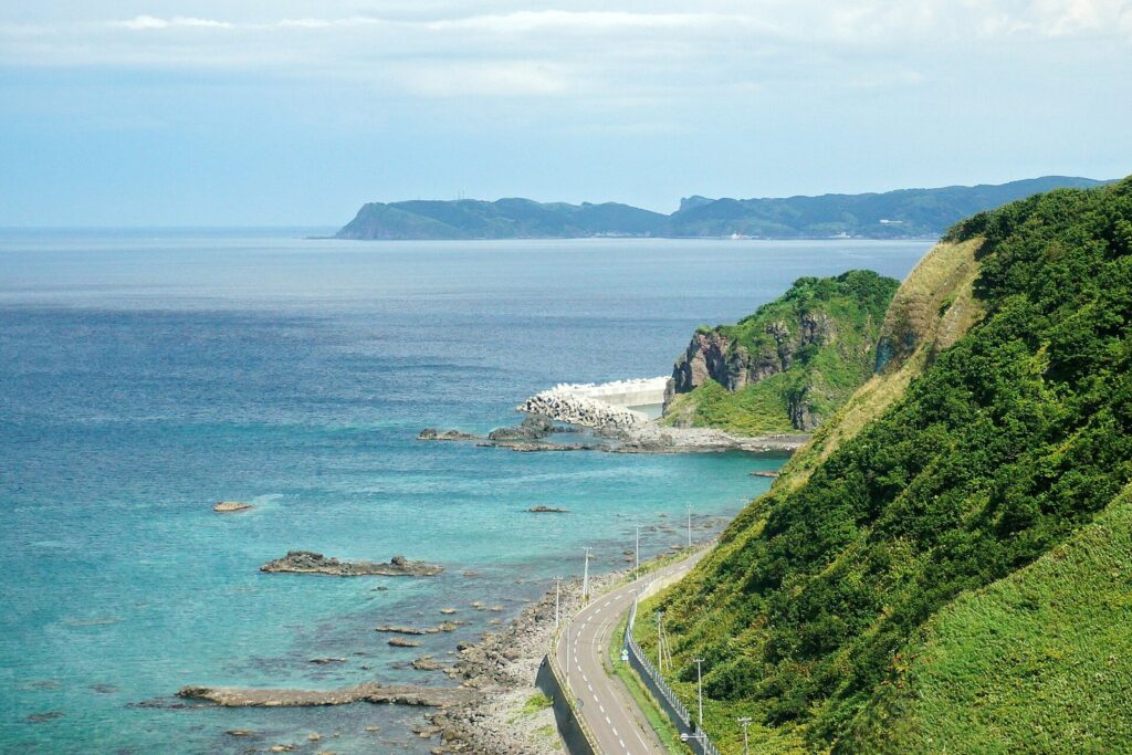 積丹岬周辺の緑の断崖と青い海、海沿いの道路