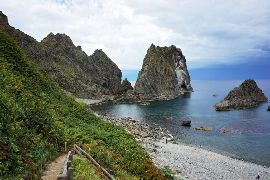 遊歩道の先に岩礁と透き通った青い海が広がる島武意海岸