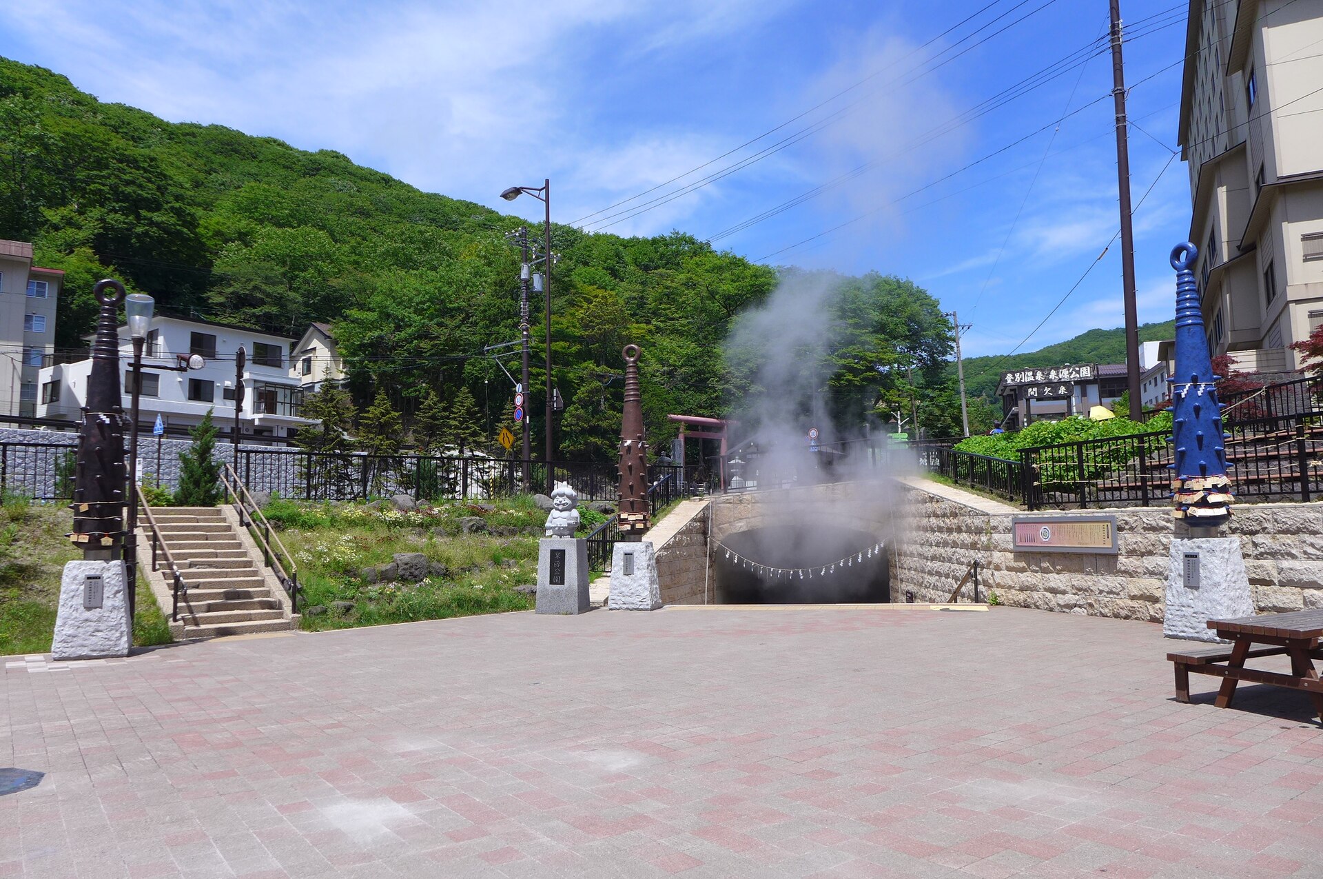 登別温泉街の泉源公園で湯けむりを上げる泉源と、鬼の金棒をかたどったモニュメント